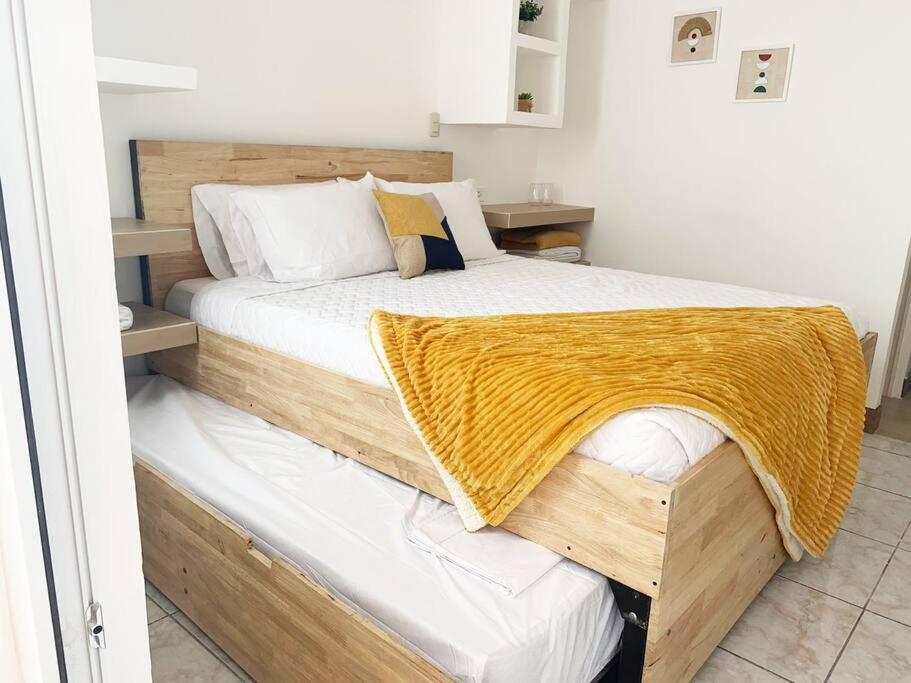 Un dormitorio con una cama de madera con una manta amarilla. en Great apartment D1 en Guatemala