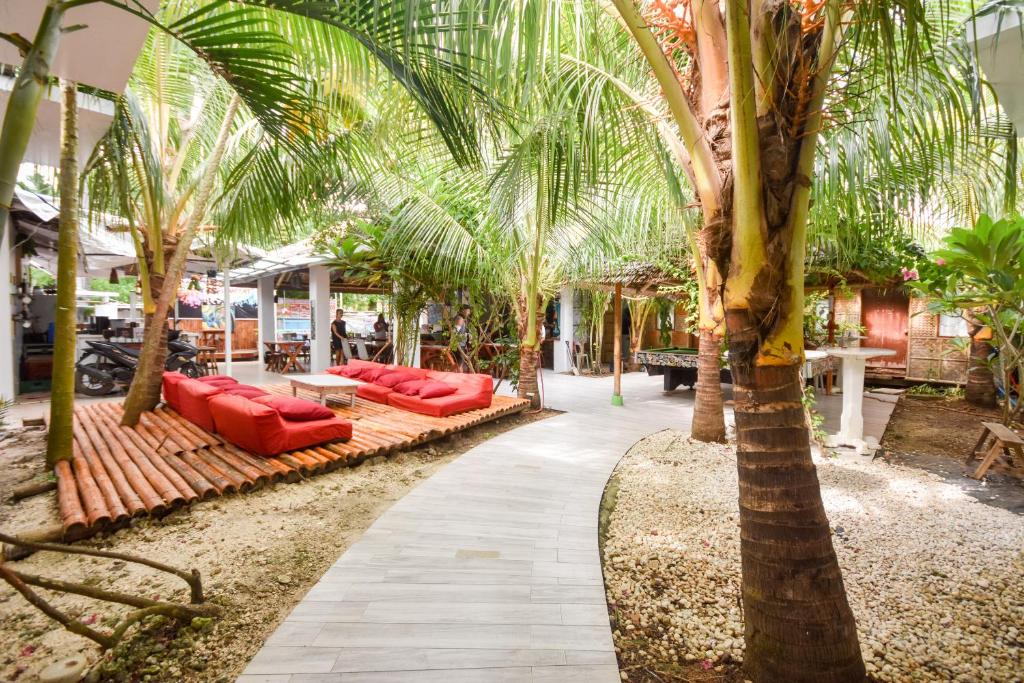 a row of red couches sitting under palm trees at Boracay Backpackers in Boracay
