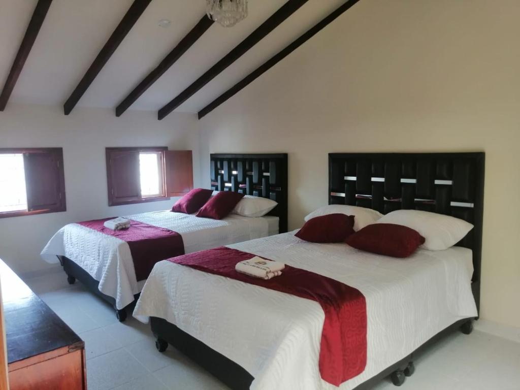 um quarto com 2 camas com lençóis vermelhos e brancos em Hotel Castillo Real em Popayán