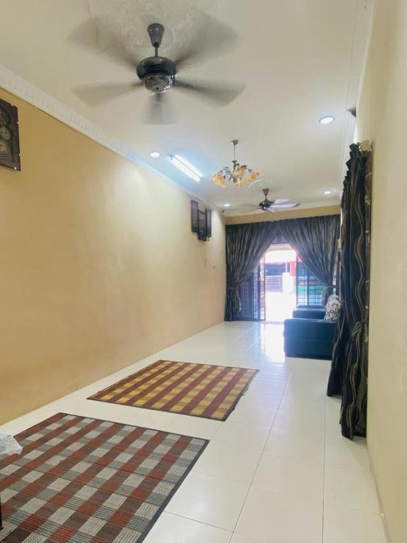 uma sala de estar com uma ventoinha de tecto e um sofá em Homestay lagenda padang serai em Padang Serai
