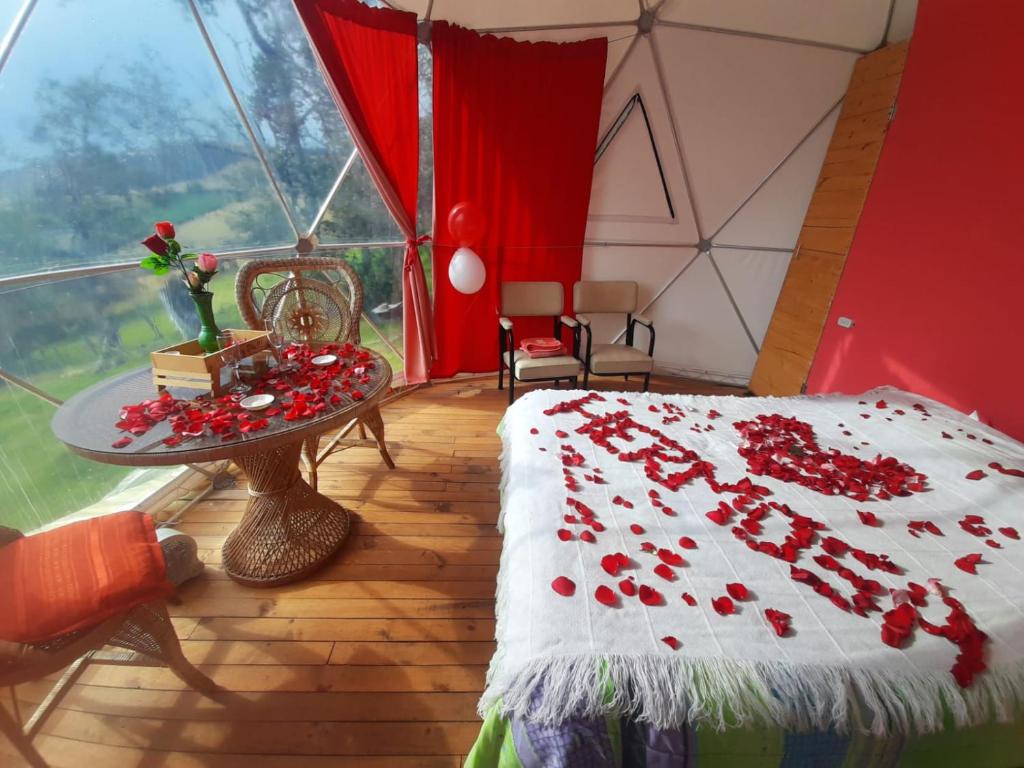 una habitación con una cama y una mesa con rosas. en Glamping Mi Casita en Guatavita