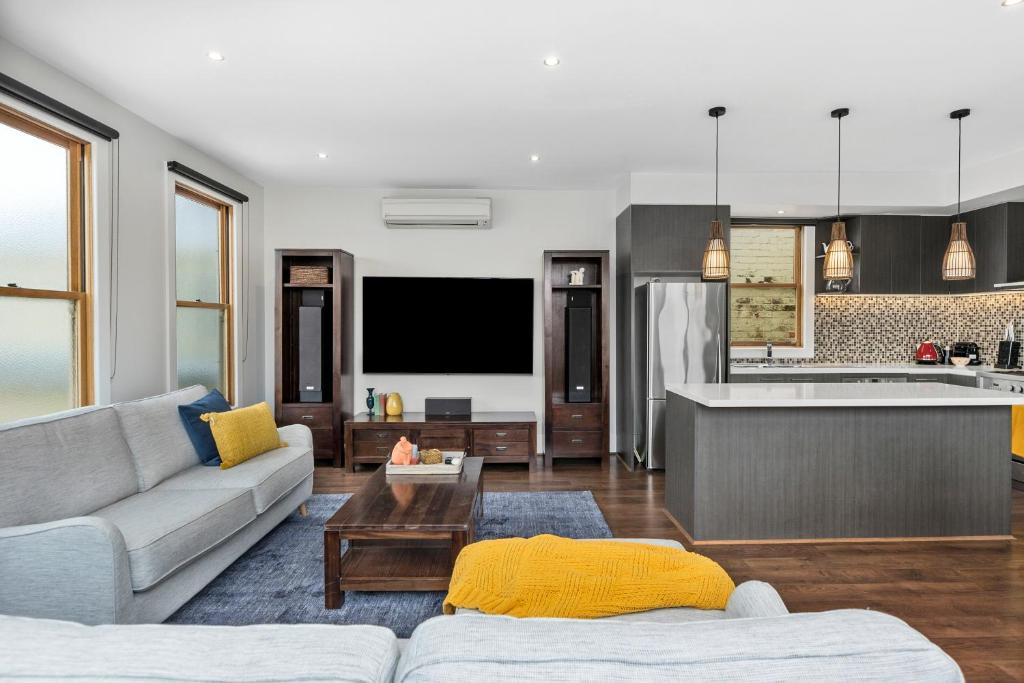 a living room with a couch and a kitchen at The SCOOP in Queenscliff