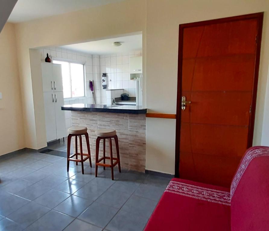 uma cozinha com um balcão e dois bancos num quarto em Apartamento super arejado na Praia do Morro em Guarapari