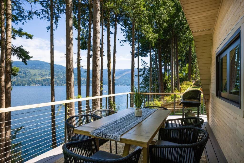 un tavolo e sedie su un balcone con vista sull'acqua di Casa Las Nubes NEW! Whatcom Lakefront Cabin/HotTub a Bellingham