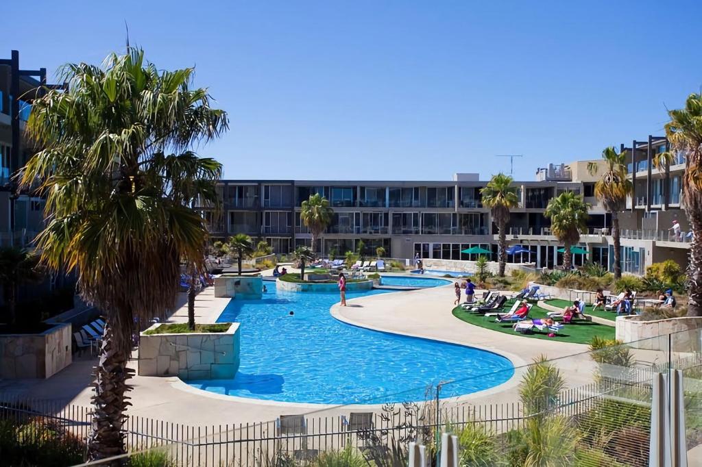 Una piscina en un resort con palmeras y un edificio. en Resort Penthouse 301, en Torquay