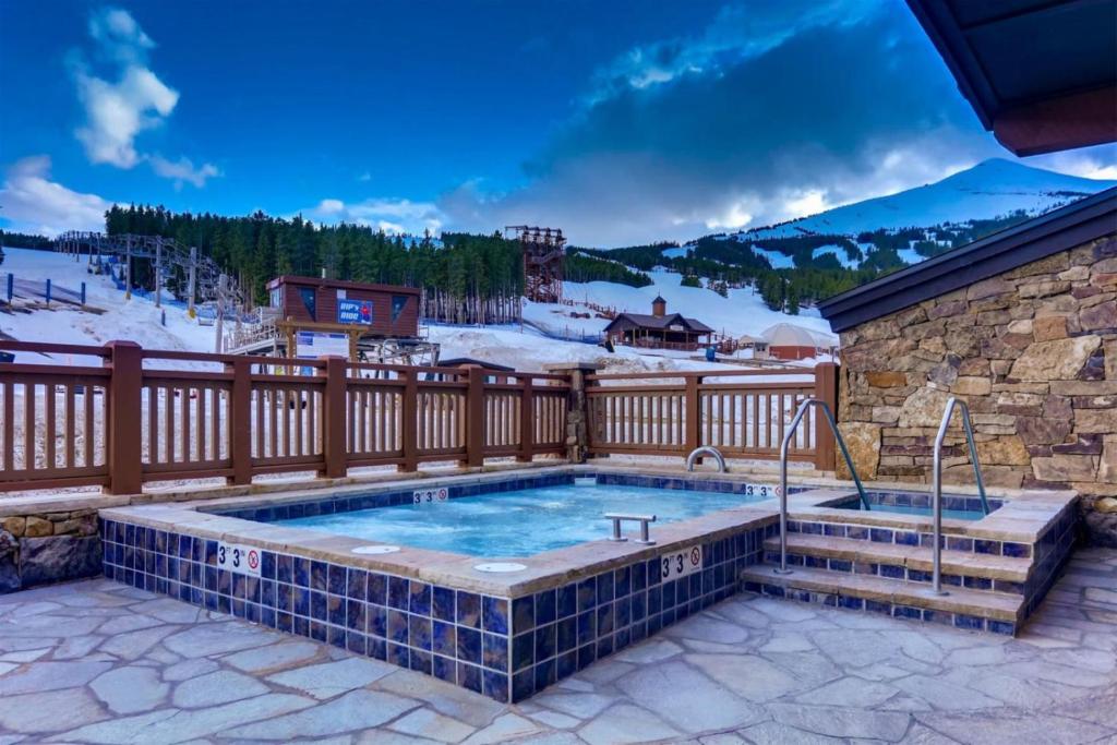 a hot tub on a patio with a fence at Luxury 1 Bedroom Ski In, Ski Out One Ski Hill Residence Located At The Base Of Peak 8 With Bowling Alley Onsite in Breckenridge
