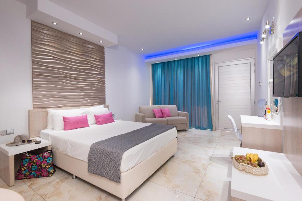 a bedroom with a large white bed and a bathroom at Loutsiana Deluxe Apts in Ayia Napa