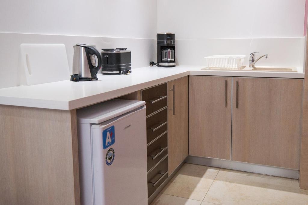 a kitchen with a counter and a sink and a dishwasher at Loutsiana Deluxe Apts in Ayia Napa