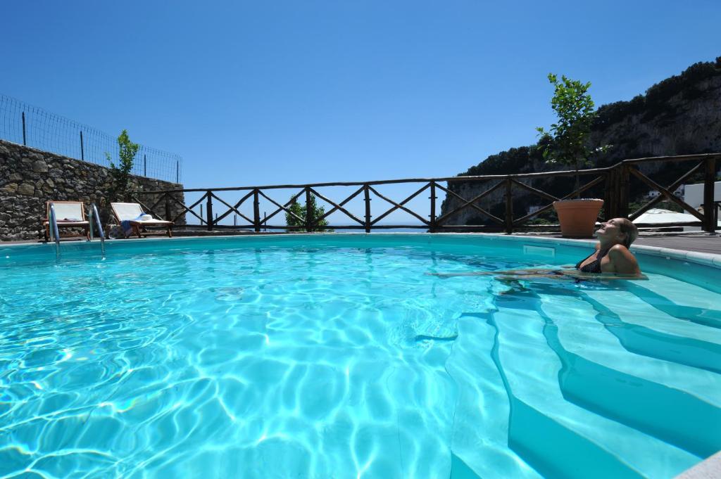 une femme se pose dans une piscine bleue dans l'établissement Villa Knight, à Amalfi