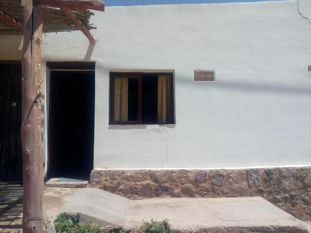 - un bâtiment blanc avec une porte et une fenêtre dans l'établissement ElPoro, à Purmamarca