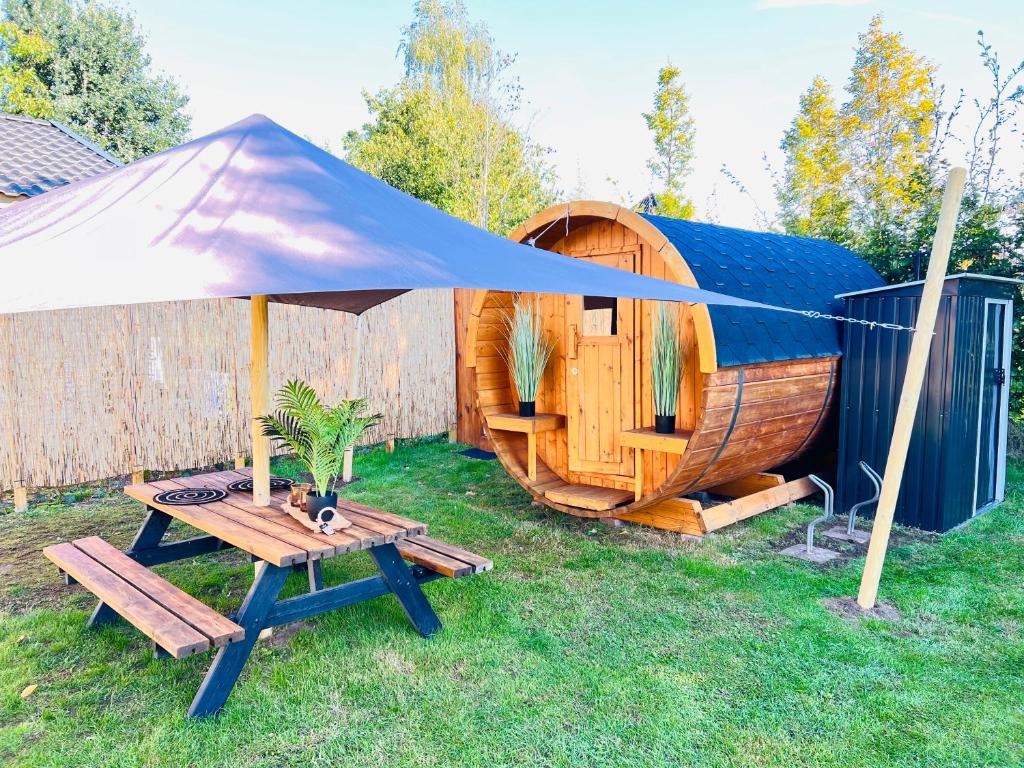 a small wooden cabin with a table and a tent at de Harmonie in Molenhoek