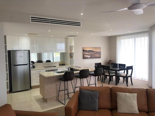 a kitchen and living room with a couch and a table at Grand Mercure Allegra Hervey Bay in Hervey Bay