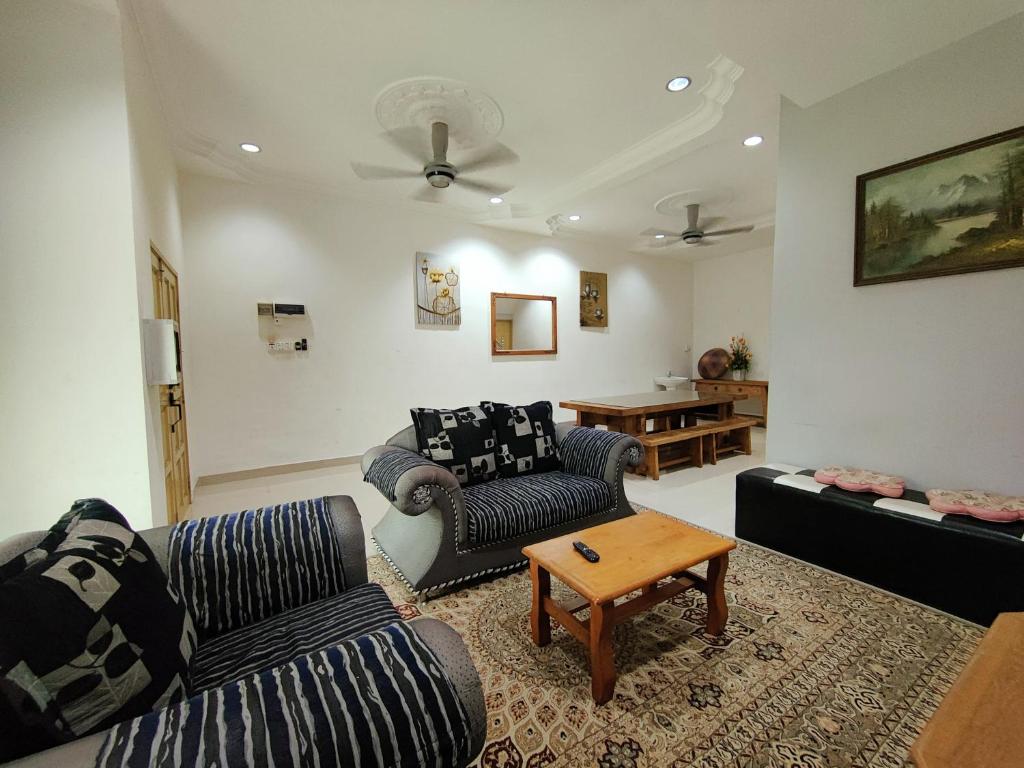 ein Wohnzimmer mit zwei Sofas und einem Tisch in der Unterkunft Homestay Roma Suite in Kuala Terengganu