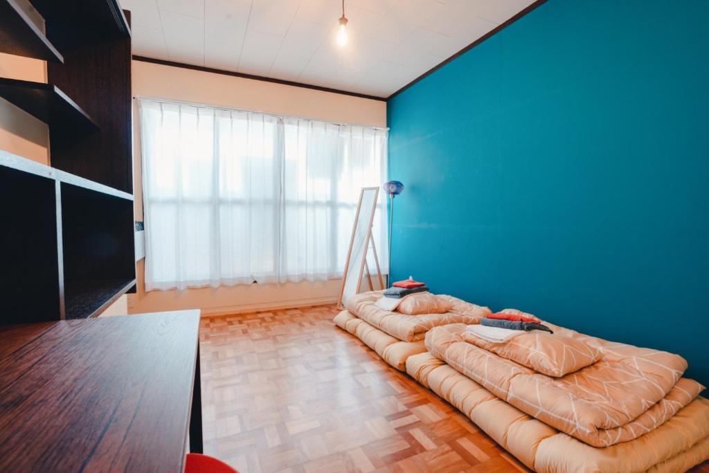 a room with two beds against a blue wall at SLOW HOUSE kesennuma - Vacation STAY 30922v in Kesennuma