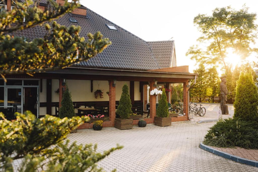 een gebouw met een veranda met bomen ervoor bij Holiday Stary Folwark in Suwałki