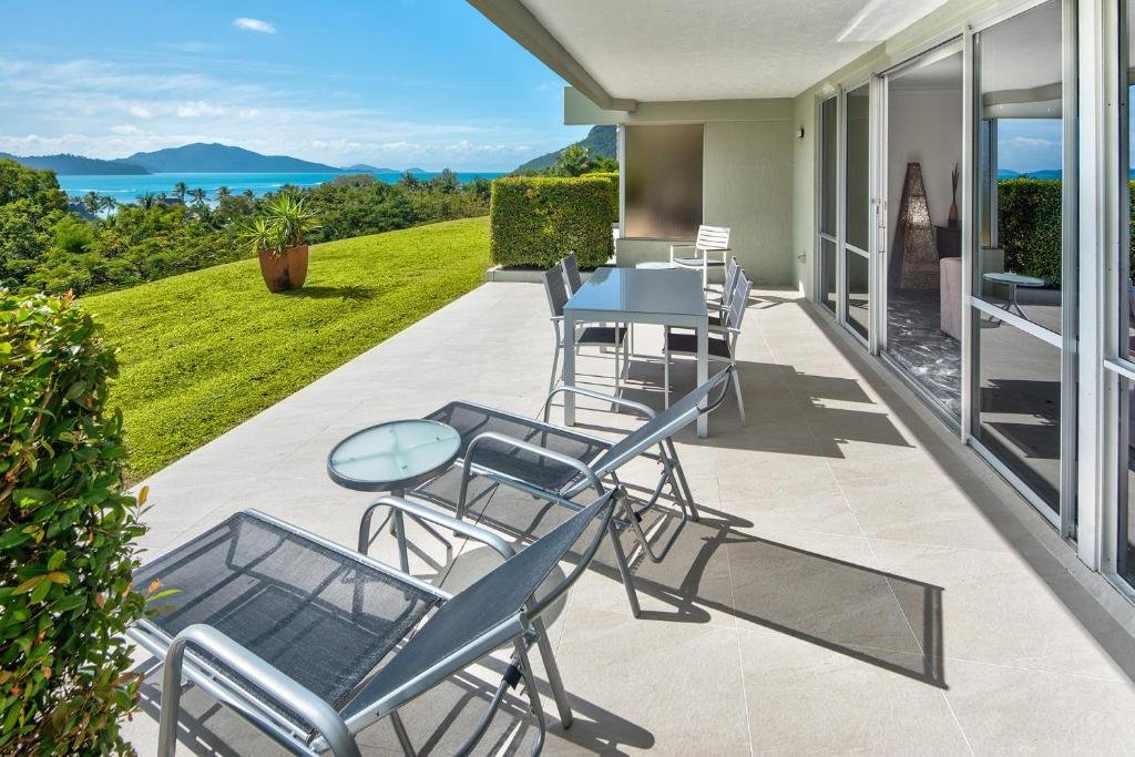 a patio with a table and chairs on a balcony at 3 Bedroom Poinciana Lodge in Hamilton Island