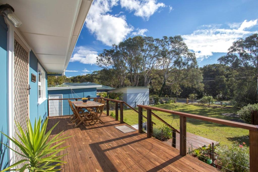 a wooden deck with a table on a house at Retro Beach Cottage in Kioloa