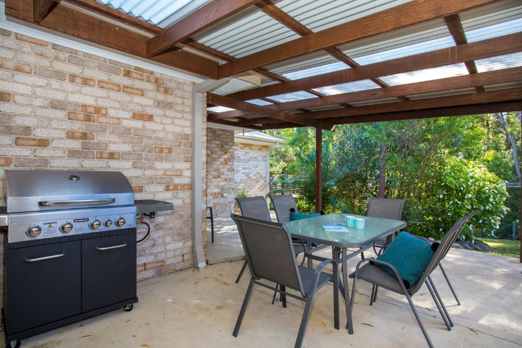 a patio with a grill and a table with chairs at Leafy Retreat in Ulladulla