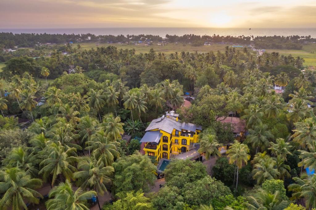 an aerial view of a yellow building in the middle of trees at Whoopers Boutique Hotel, Anjuna in Anjuna