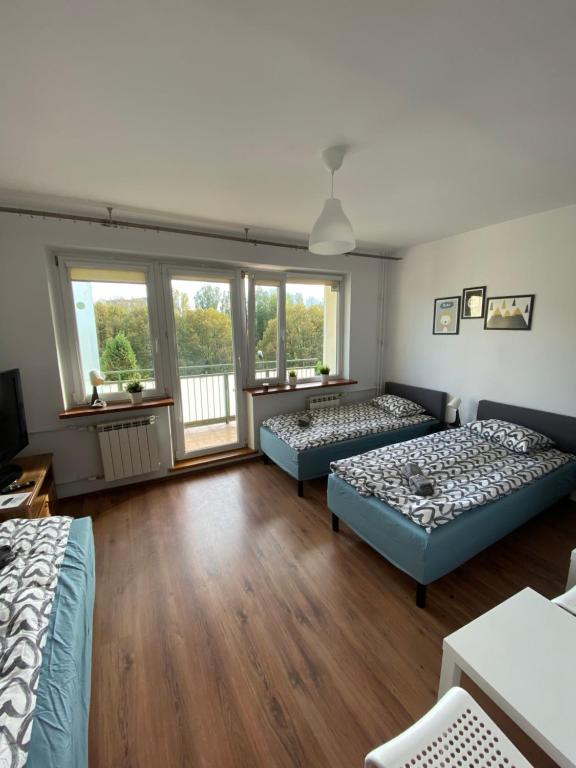 2 łóżka w pokoju z drewnianymi podłogami i oknami w obiekcie Pokoje Bora-Komorowskiego w Warszawie
