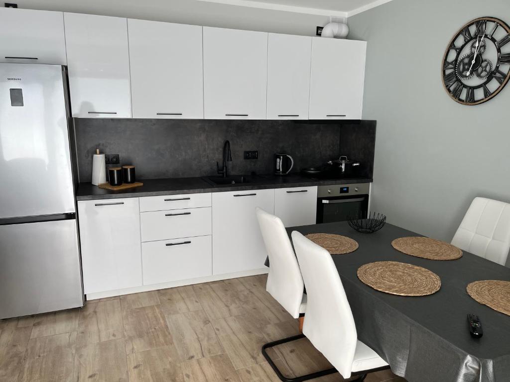 a kitchen with white cabinets and a table and a refrigerator at Apartament Widok&Sky Piechowice/Szklarska Poręba in Piechowice