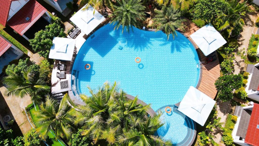 an overhead view of a swimming pool with umbrellas and palm trees at Fla Village in Phú Quốc