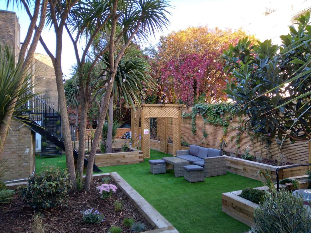 einen Garten mit Sofa, Bäumen und Gras in der Unterkunft Swinton Hotel in London