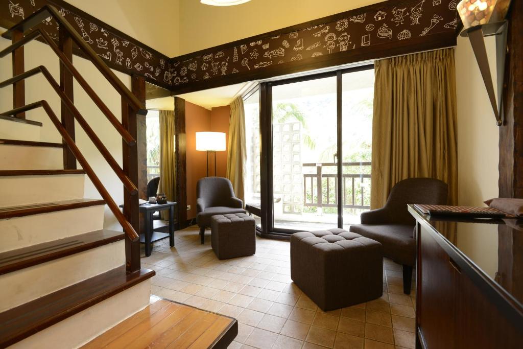 a living room with a staircase and chairs and a window at Yoho Beach Resort Kenting in Hengchun
