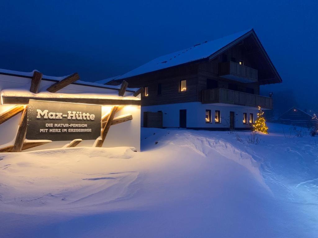 a building with a sign in the snow at night at Naturpension Max-Hütte in Breitenbrunn