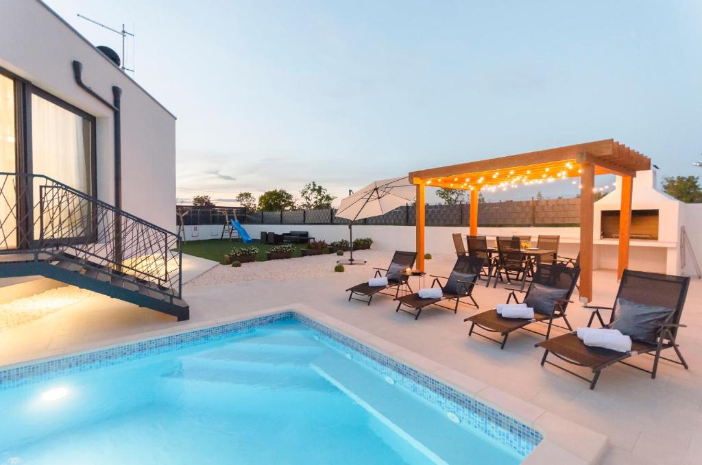 een patio met een zwembad en stoelen en een tafel bij Villa Laurel in Skradin