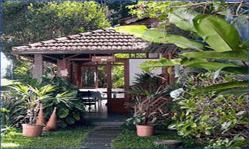 una casa con porche con mesa y plantas en Pousada Vale das Hortensias, en Visconde De Maua