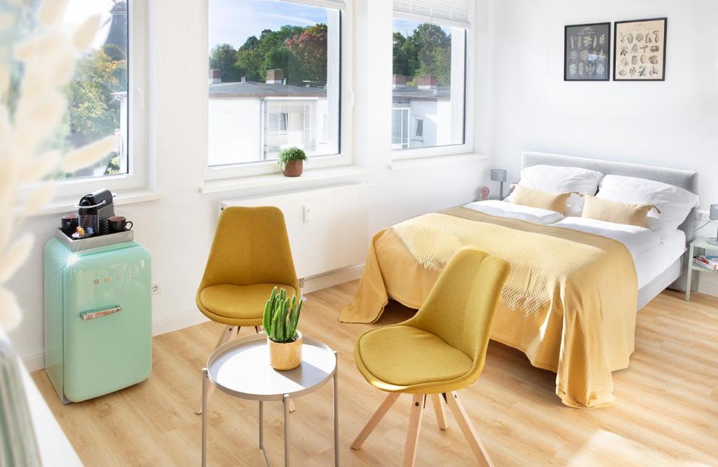 a bedroom with a bed and two chairs and a cactus at Louis & Louise Apartments & Rooms I Digital Check In in Bremen