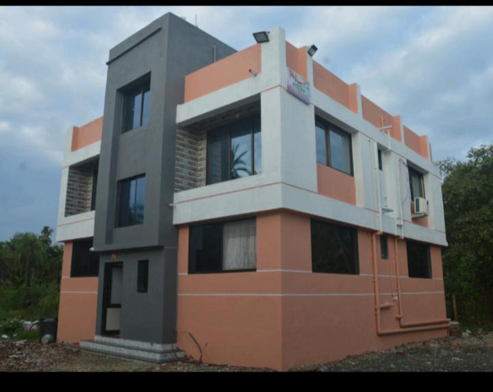 a orange and white building with trees in the background at RJ Villa farmhouse in Daman