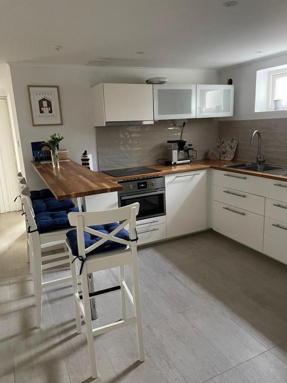 uma cozinha com armários brancos e uma mesa e cadeiras de madeira em Sommar på Smögen! em Smögen