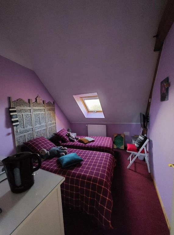 two beds in a room with purple walls at Le Relais De L&#39;Aube in Villers-Bretonneux