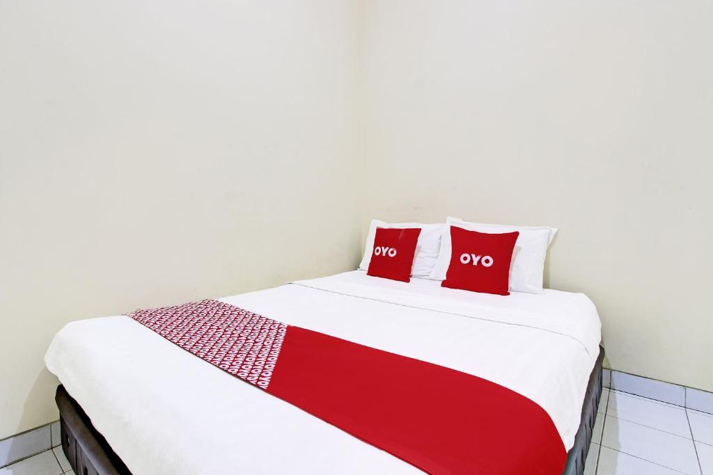 Una cama con dos almohadas rojas encima. en OYO 91803 Gita Graha Guest House Syariah en Yogyakarta