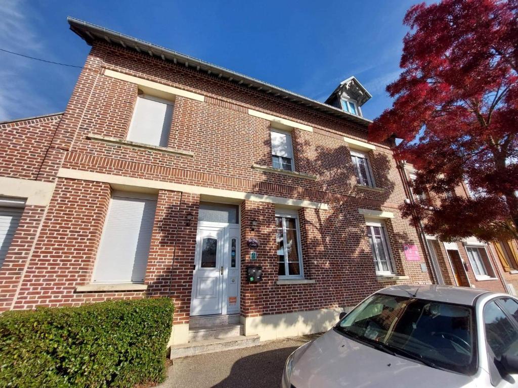 a brick house with a car parked in front of it at Le Relais De L'Aube in Villers-Bretonneux