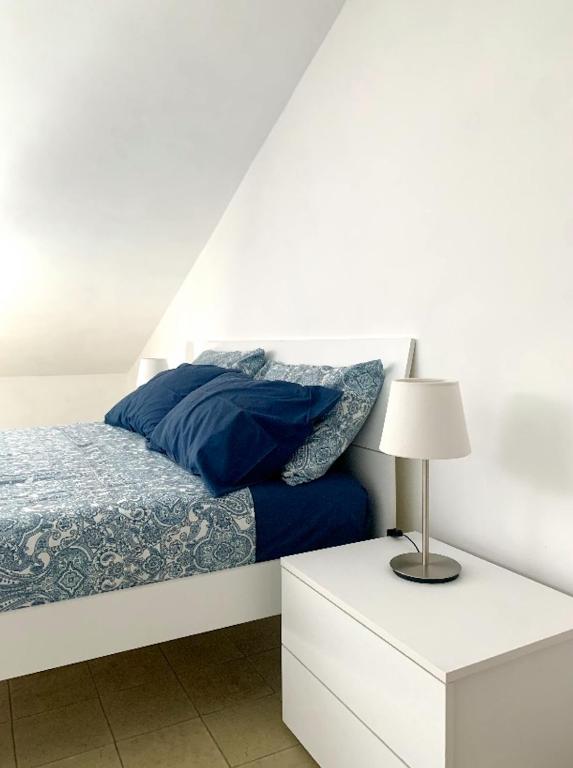 una camera da letto bianca con un letto con lenzuola blu e una lampada di APPARTAMENTO SFERISTERIO a Macerata