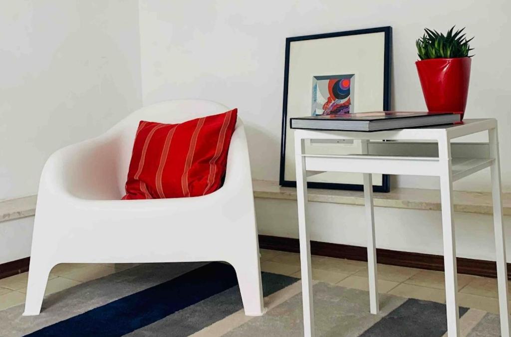 a white chair next to a table with a red pillow at APPARTAMENTO SFERISTERIO in Macerata