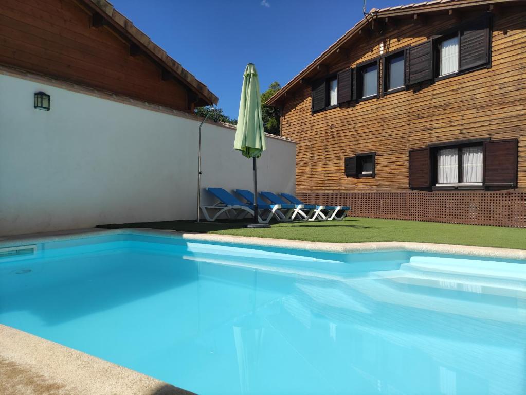 a swimming pool with an umbrella next to a house at Casa Rural La Dehesa de Toledo a 5 minutos de Puy du Fou España in Cobisa