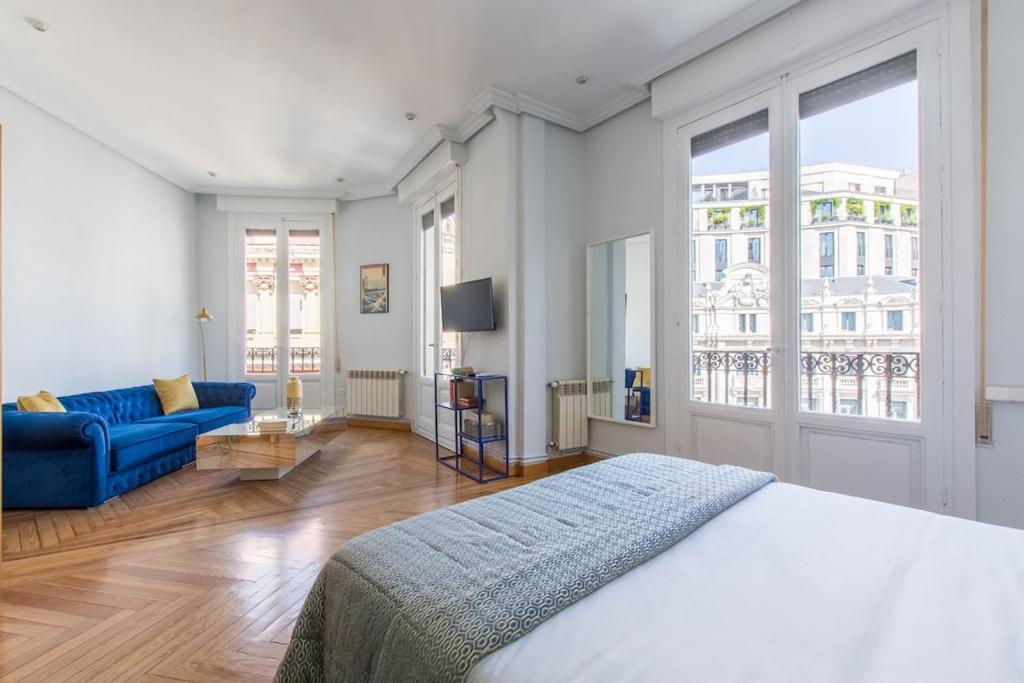 a bedroom with a bed and a blue couch at Impresionantes vistas Skyline Madrid in Madrid