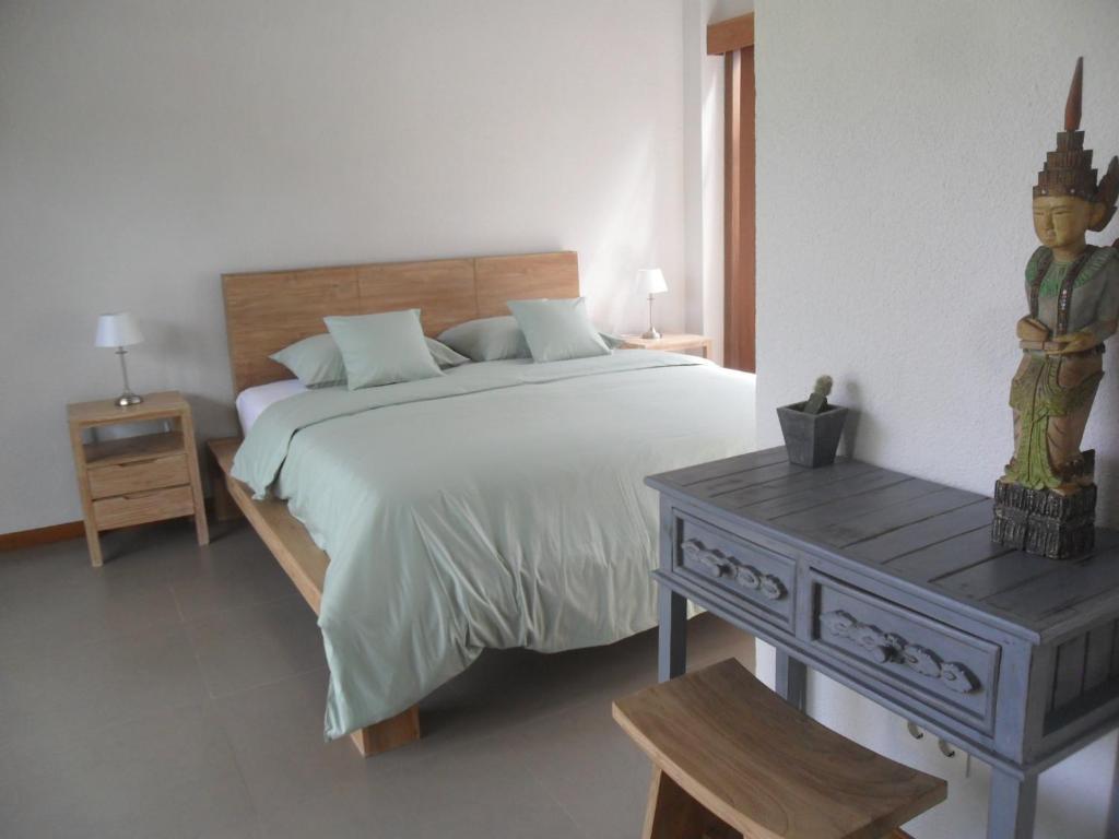 a bedroom with a large bed and a wooden table at Ju'Blu Hotel in Lovina
