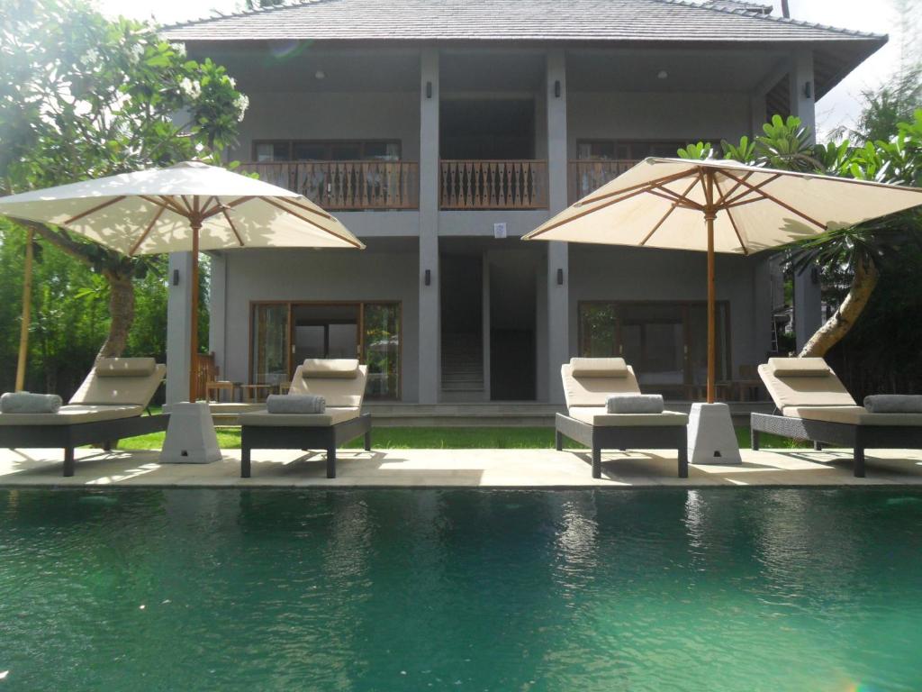 a resort with chairs and umbrellas next to a swimming pool at Ju'Blu Hotel in Lovina