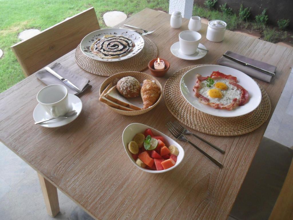 a wooden table with a breakfast of eggs and fruit at Ju'Blu Hotel in Lovina