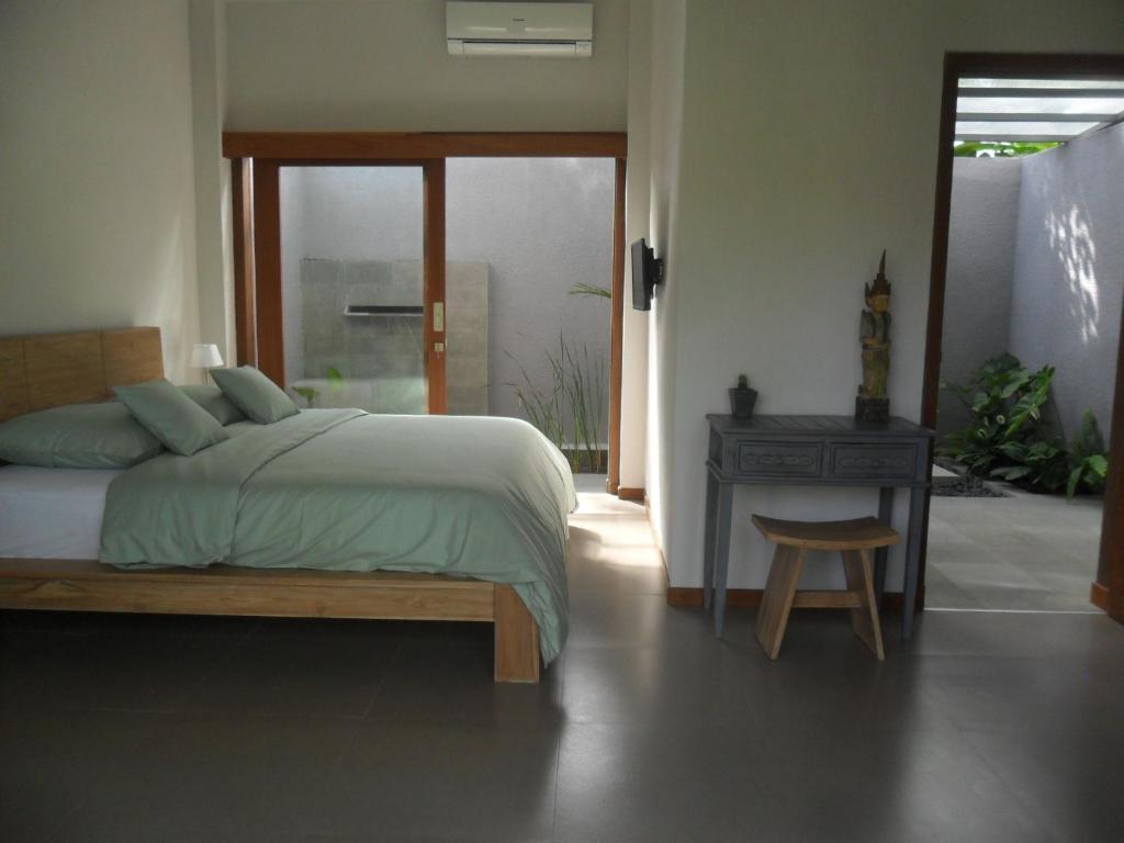 a bedroom with a bed and a table and a chair at Ju'Blu Hotel in Lovina