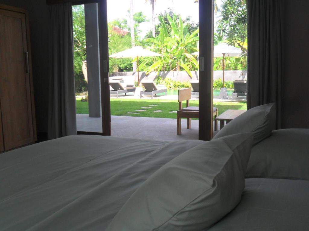 a bedroom with a bed and a view of a patio at Ju'Blu Hotel in Lovina