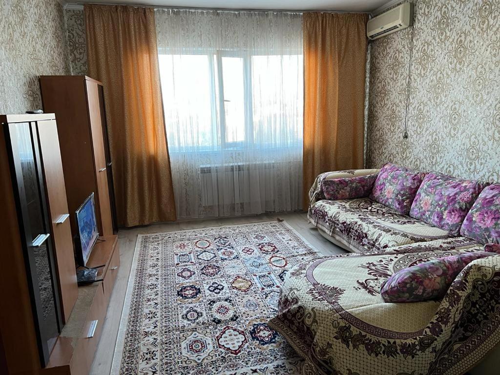 ein Wohnzimmer mit einem Sofa und einem großen Fenster in der Unterkunft 2 х комнатная квартира in Schymkent