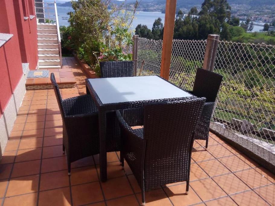una mesa y sillas en un patio con vistas en Apartamento con terraza y vistas al mar, en Bueu