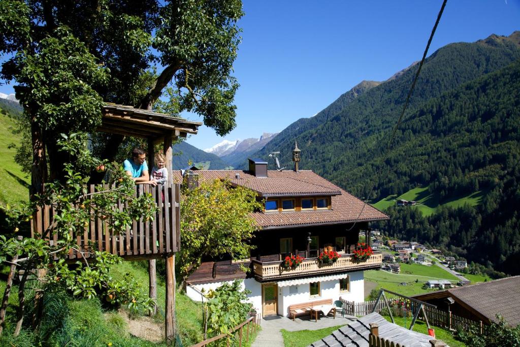 une femme sur un balcon d'une maison dans les montagnes dans l'établissement Panorama-Apartments Oberkofl, à Cadipietra