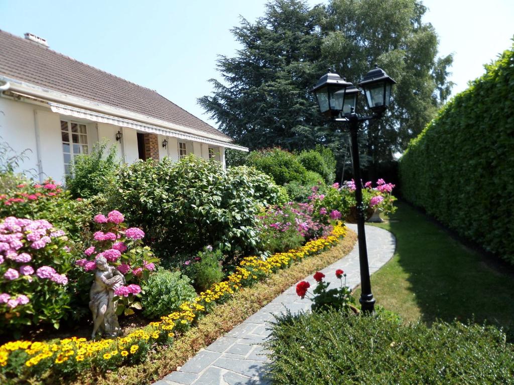 a garden with a lamp post and flowers at Les Puits Bessin Normandie in Sommervieu